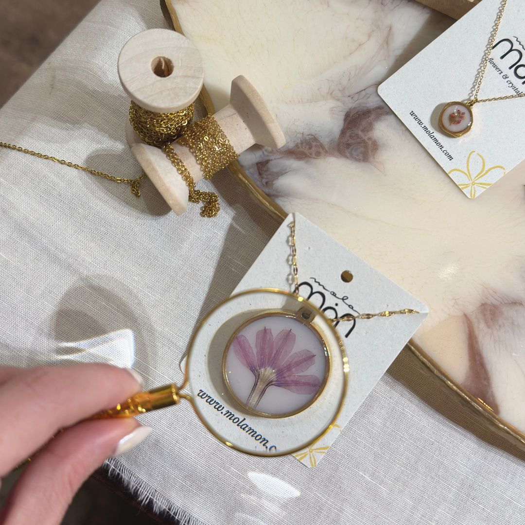 Round gold necklace with a lilac natural flower in resin, next to the gold chains to choose from at the MolaMon workshop